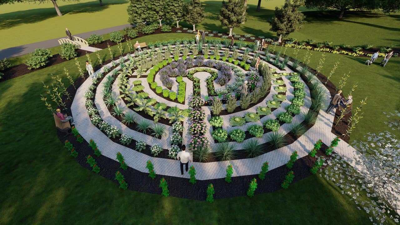 Circular garden with pathways and diverse plants, surrounded by people enjoying nature. Pathway leads to a small bridge.