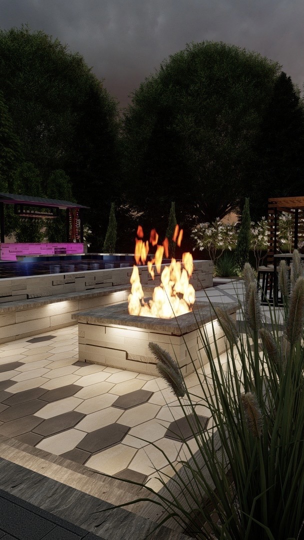 Modern patio with hexagonal tiles features a lit firepit. Surrounded by greenery, creating a cozy ambiance under the cloudy sky.