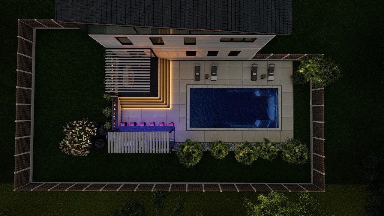 Aerial view of modern house with illuminated patio, pool, lounge chairs, and surrounding greenery within fenced yard at night.