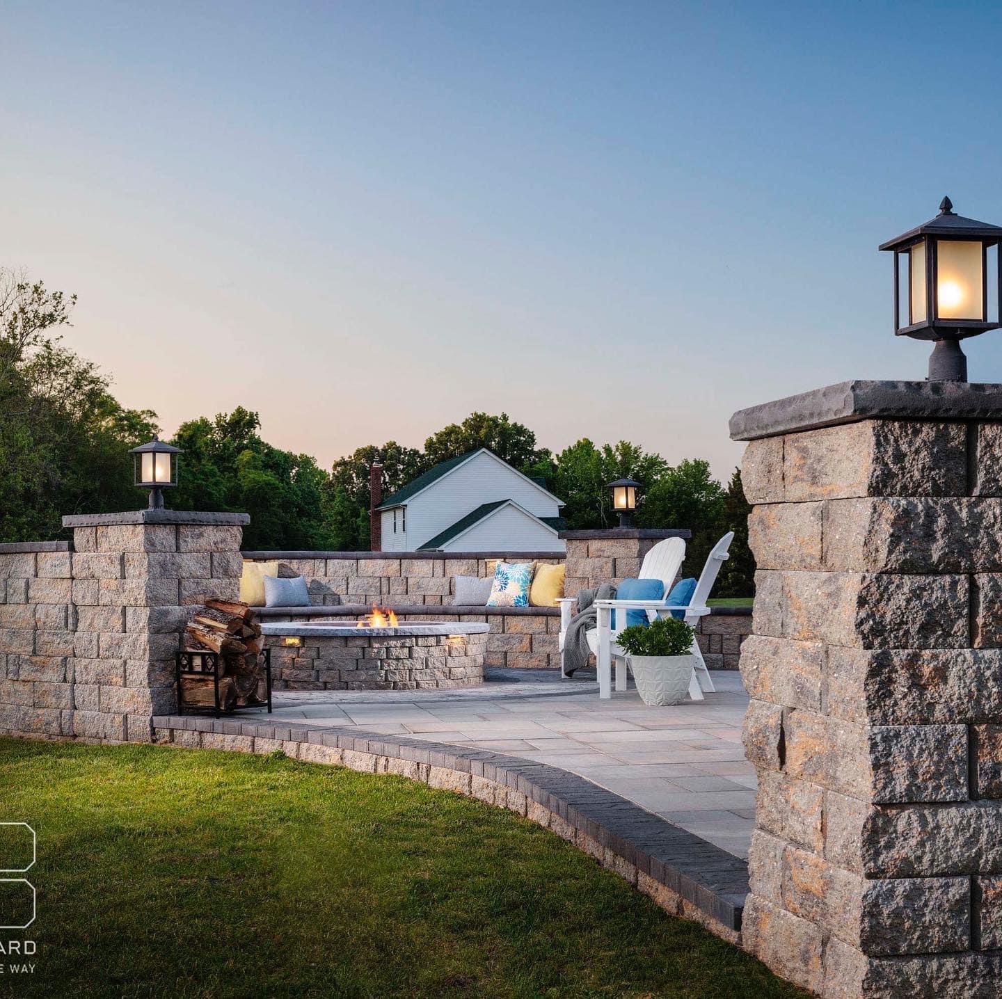 Stone patio with built-in seating, a fire feature, and decorative pillar lighting.