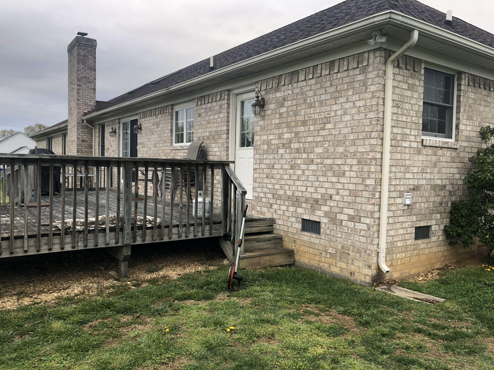 Weathered wooden deck attached to a brick house before renovation.