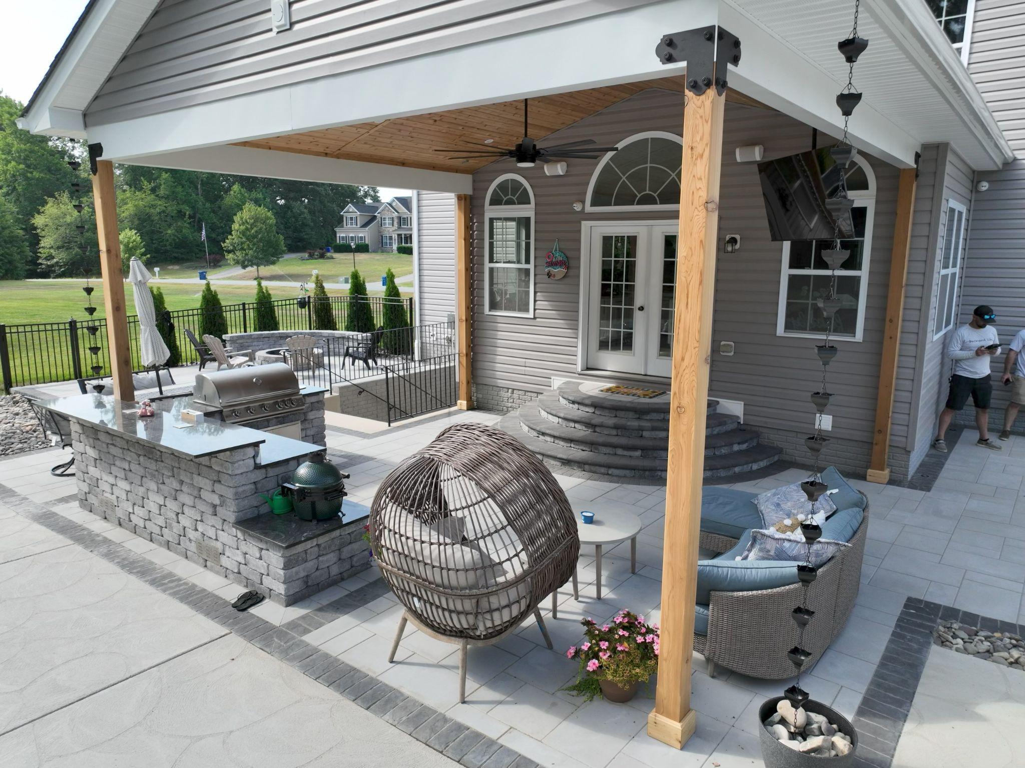 Spacious covered patio with an outdoor kitchen, seating area, and decorative hardscaping.