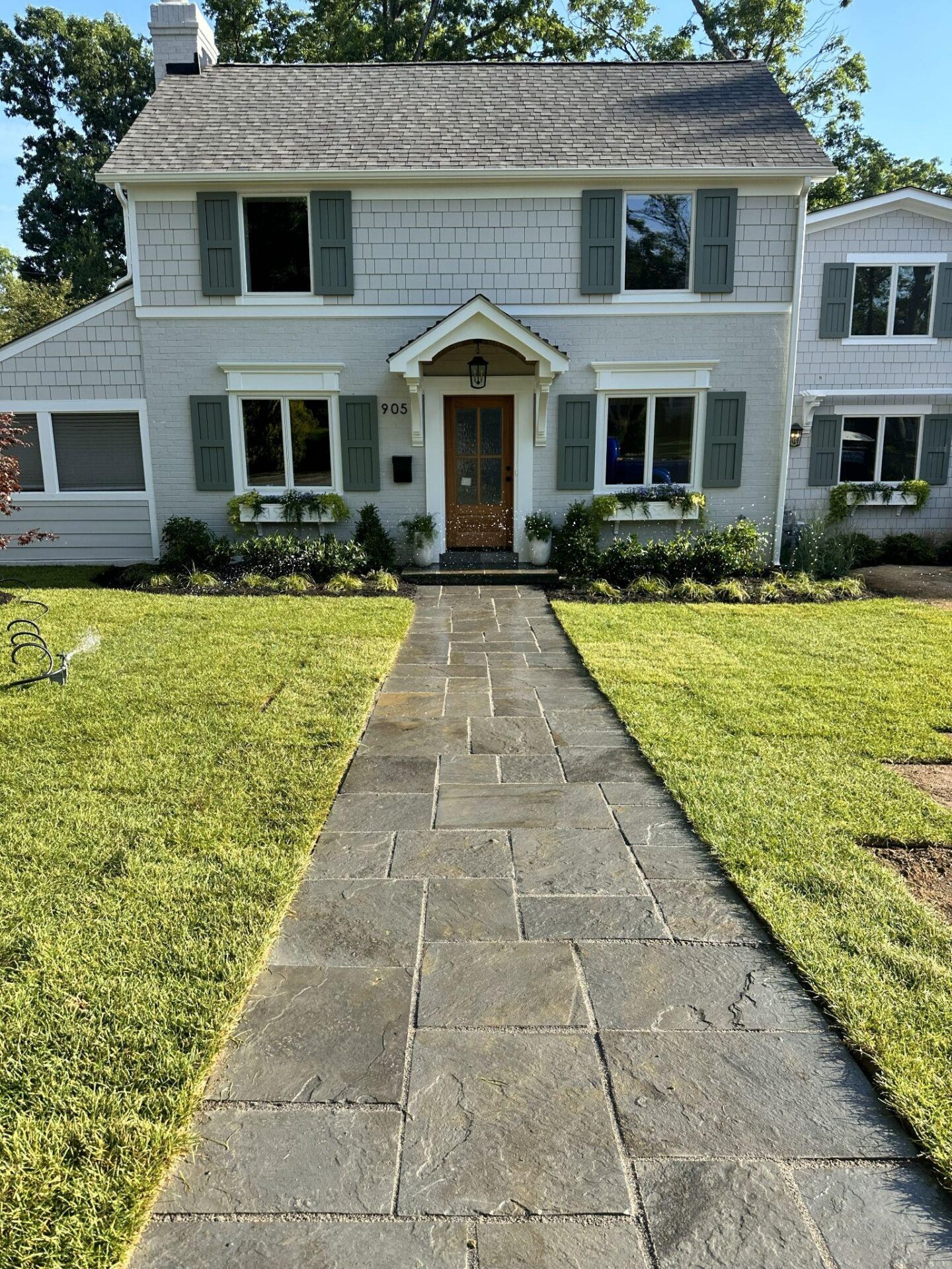 Straight bluestone walkway leading to the front door of a home with fresh landscaping.